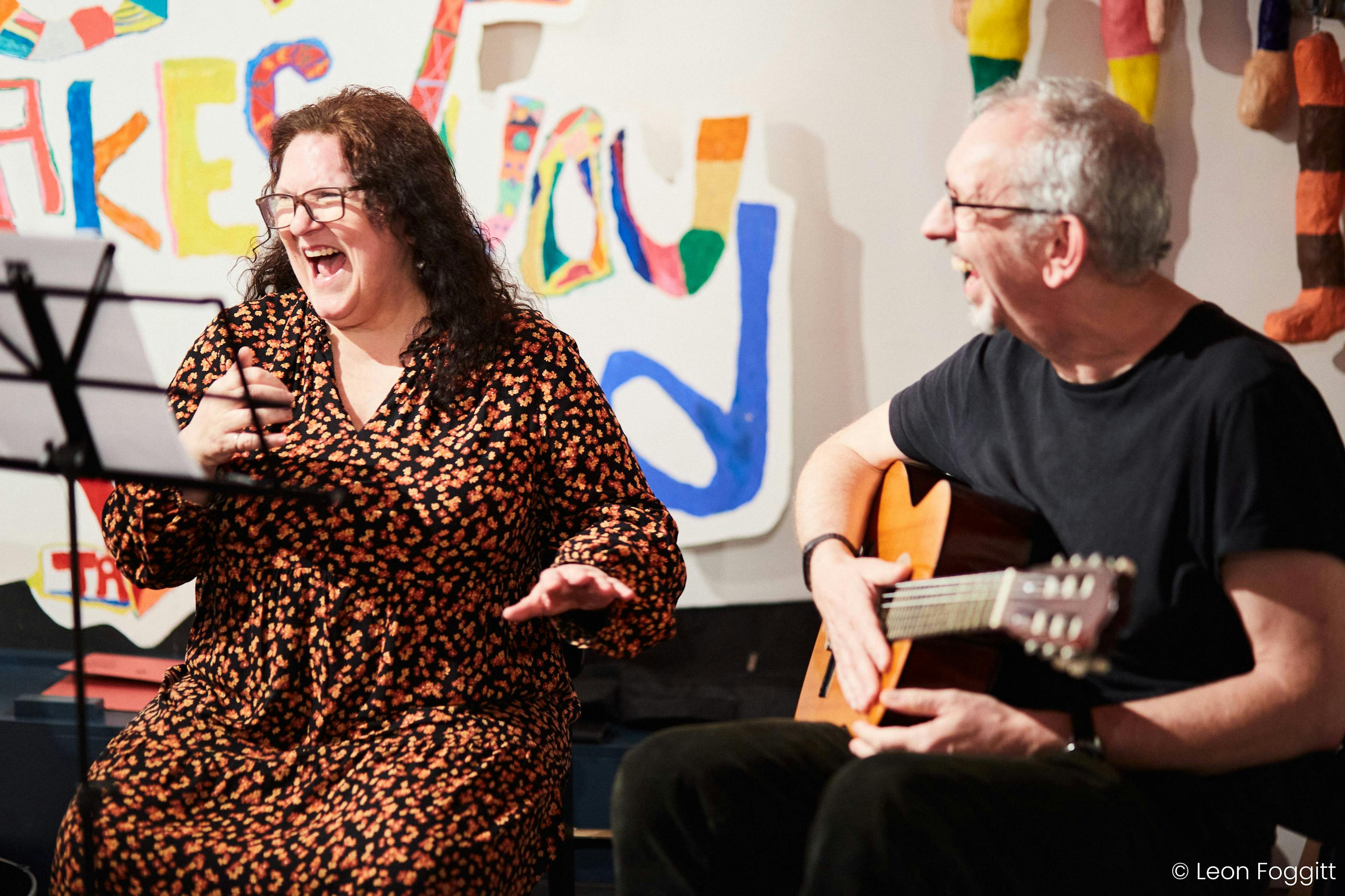 James Compton playing guitar next to a smiling woman