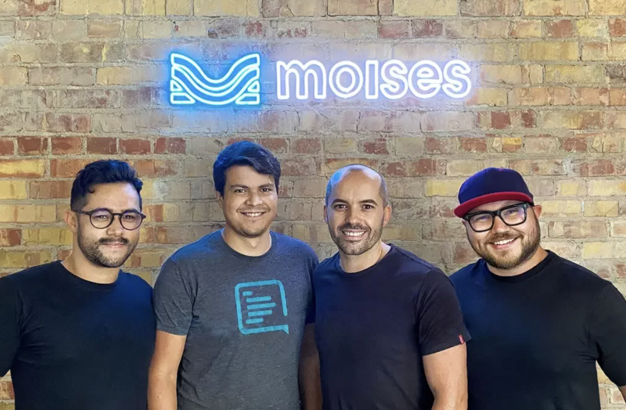 Part of Moises' leadership with a sign with the Moises logo in the background